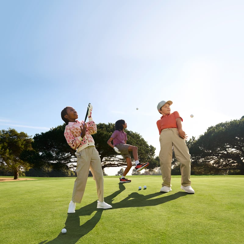 Three youth golfers joyfully play around on a beautifully maintained course